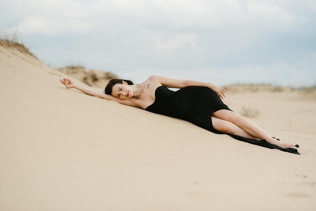 Ragazza in un abito lungo nero in un deserto sabbioso