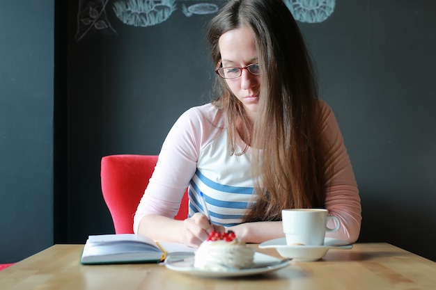 Ragazza in un bar per una tazza di caffè con il taccuino