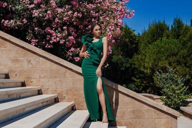 Ragazza in un bel vestito elegante verde nel parco