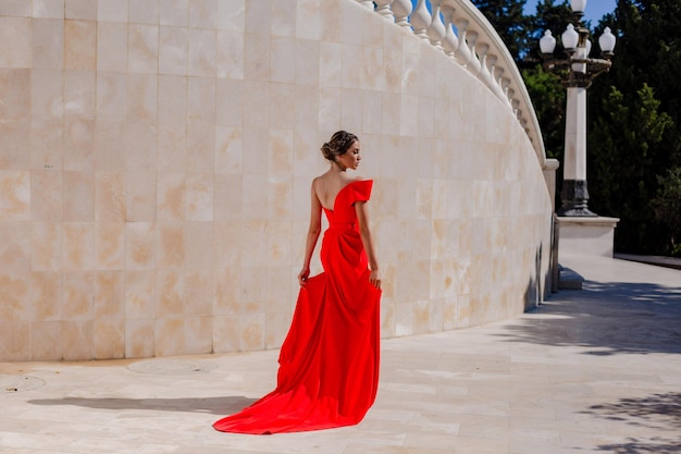 Ragazza in un bel vestito rosso elegante nel parco