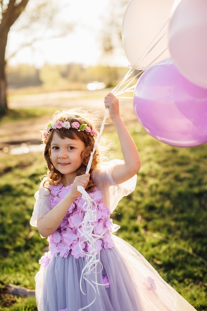 Ragazza in un bello vestito viola che gioca con gli aerostati nel parco