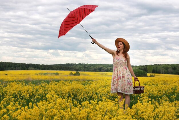 Ragazza in un campo di fiori con un ombrello e un cappello