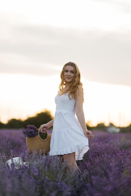 Ragazza in un campo di lavanda Donna in un campo di fiori di lavanda al tramonto in un abito bianco Francia Provenza