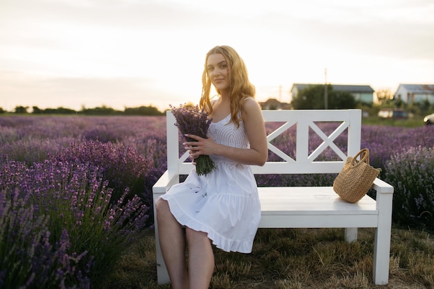 Ragazza in un campo di lavanda Donna in un campo di fiori di lavanda al tramonto in un abito bianco Francia Provenza