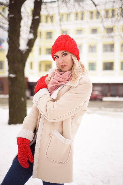 Ragazza in un cappello rosso e guanti all'aperto in inverno.