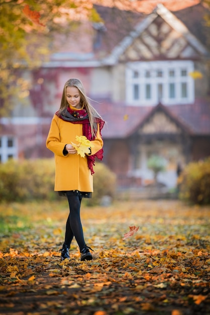 ragazza in un cappotto giallo brillante passeggiate nel parco in autunno