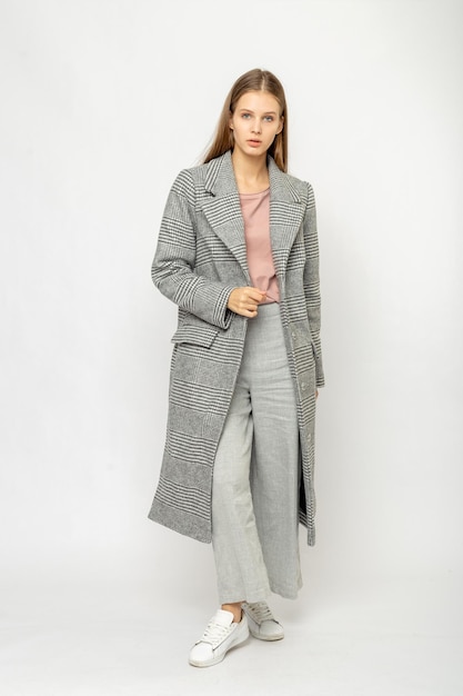 Ragazza in un cappotto grigio isolato su sfondo bianco