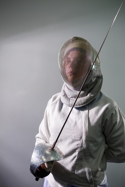 Ragazza in un costume da scherma con una spada in mano isolata su sfondo bianco per studio. Le ragazze praticano ed esercitano. Sport, stile di vita sano.