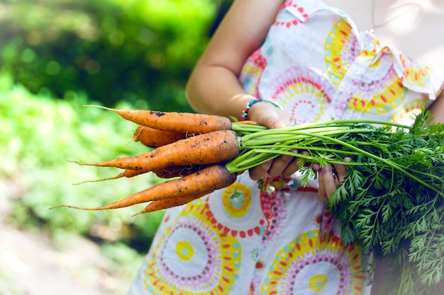 Ragazza in un giardino con in mano una carota