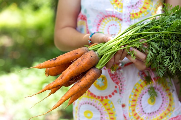 Ragazza in un giardino con in mano una carota