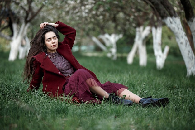 Ragazza in un giardino fiorito in un cappotto marrone