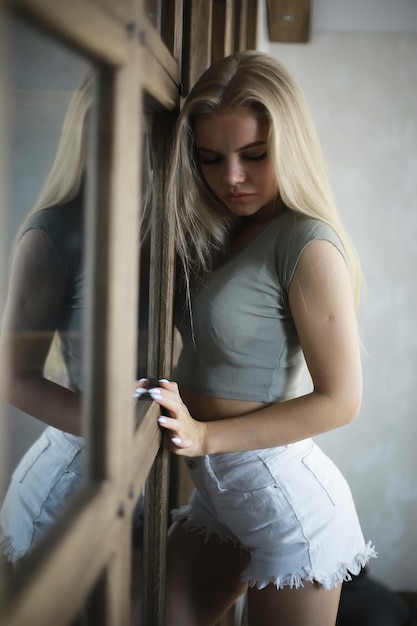 ragazza in un interno loft, casa moderna, finestre, muro. giovane adulto in posa