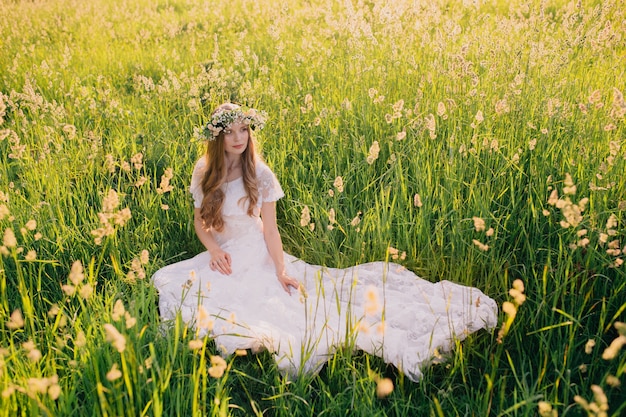 Ragazza in un vestito bianco nel prato. Donna in un bellissimo abito lungo in posa nel giardino