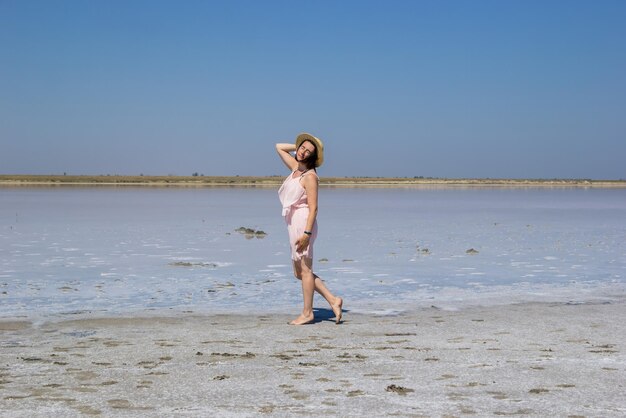 Ragazza in un vestito che va a piedi nudi lungo le rive di un lago salato