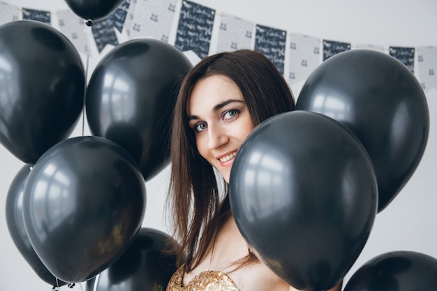 Ragazza in un vestito d'oro con palloncini neri