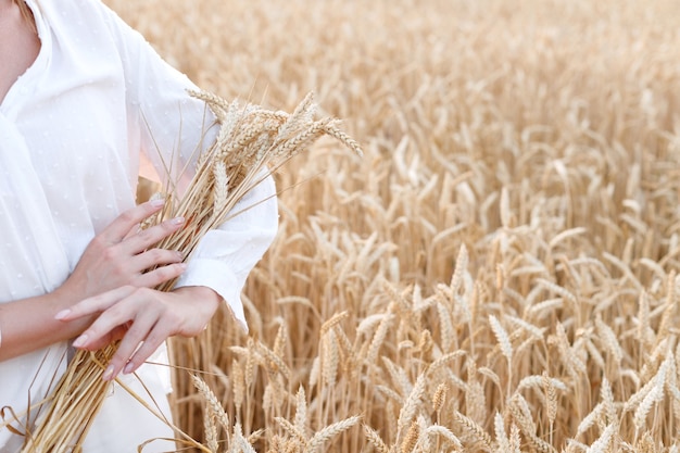 Ragazza in una camicia bianca con grano in un campo di grano primo piano