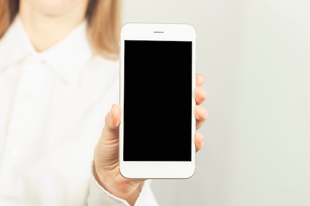 ragazza in una camicia bianca tiene in mano un telefono.