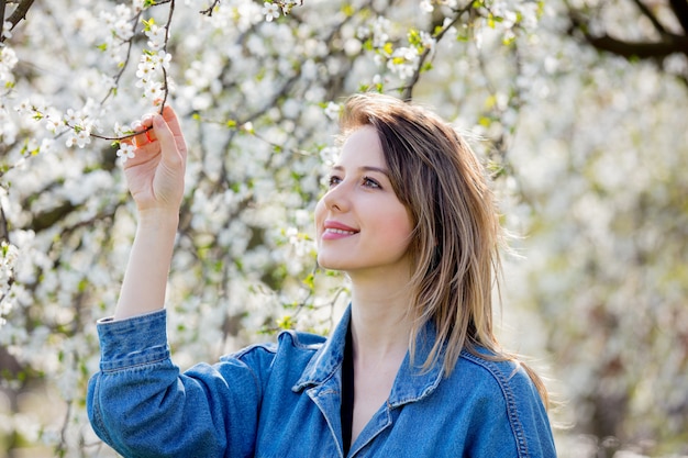 ragazza in una giacca di jeans stare vicino a un albero in fiore