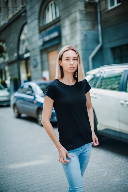 Ragazza in una maglietta nera vuota con capelli biondi in posa mockup per la tipografia di magliette