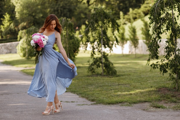 ragazza in una passeggiata con un mazzo di fiori in estate