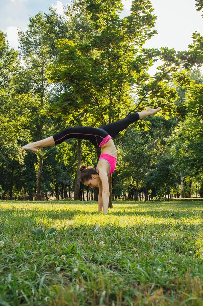 ragazza in una tuta leggera che fa yoga nel parco nel pomeriggio in estate