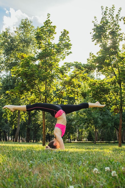 ragazza in una tuta leggera che fa yoga nel parco nel pomeriggio in estate