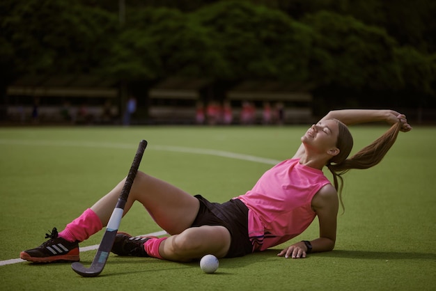 Ragazza in uniforme rosa sul concetto di hockey su prato campo di hockey su prato