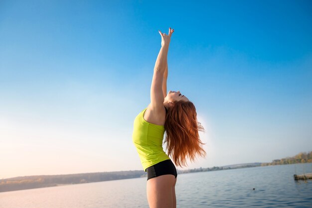 Ragazza in uniforme sportiva che riposa dopo esercizi mattutini sulla riva del lago