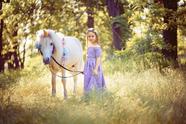 Ragazza in vestito viola che abbraccia unicorno bianco