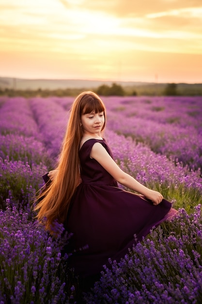 Ragazza in vestito viola divertendosi sul campo di fiore della salvia.