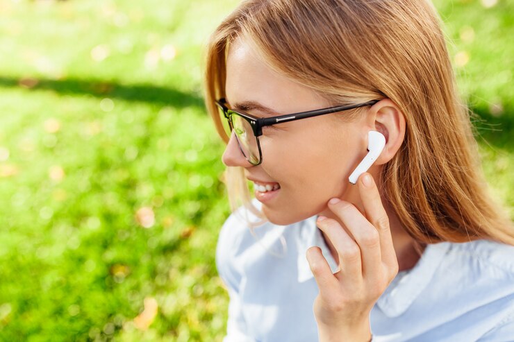 Ragazza in vetri che ascolta la musica tramite le cuffie senza fili all'aperto