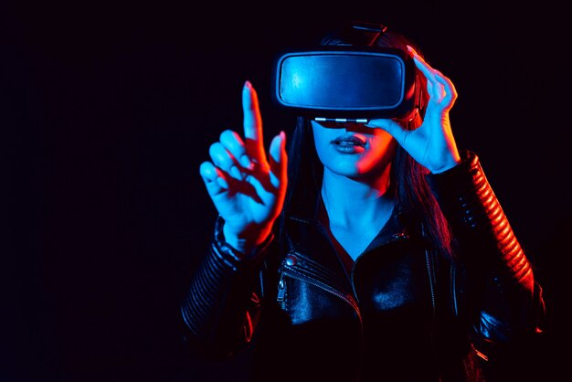 Ragazza in vetri moderni di realtà virtuale su una priorità bassa nera