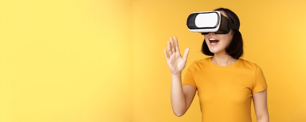 Ragazza in vr bella giovane donna asiatica che usa occhiali per realtà virtuale e gioca a chattare virtualmente ...