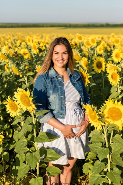 Ragazza incinta con i girasoli, ragazza felice che aspetta il bambino