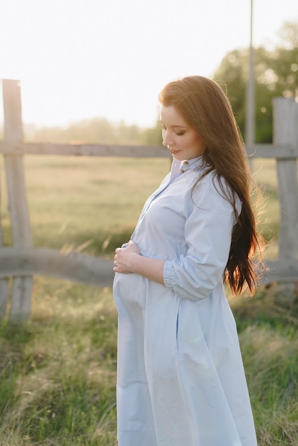 Ragazza incinta in estate all'aperto al tramonto