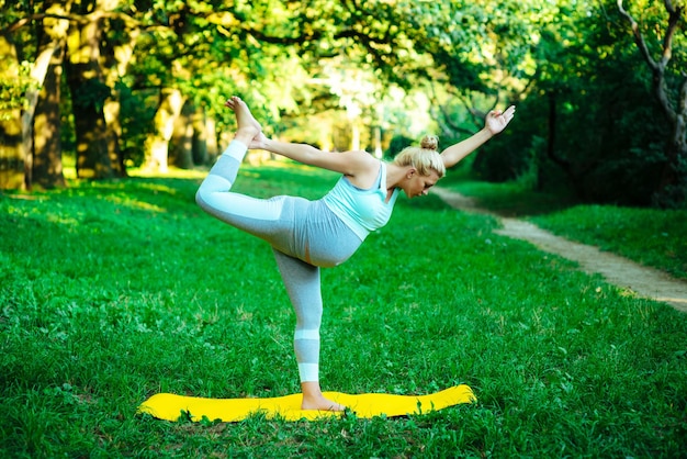 Ragazza incinta in piedi nell'asana in natura