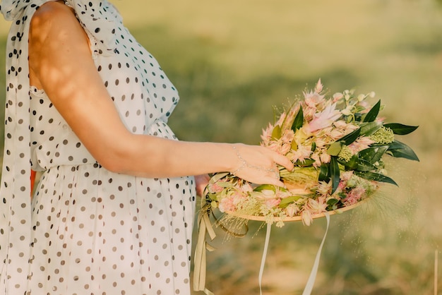 ragazza incinta in un vestito in estate che tiene un mazzo di fiori