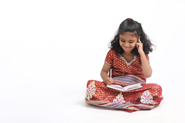 Ragazza indiana della scuola che studia su priorità bassa bianca