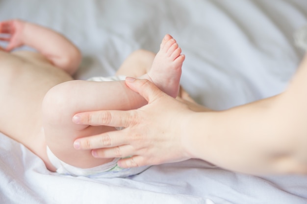 Ragazza infantile felice che fa il massaggio del bambino da sua madre a casa. Neonato di circa 5 mesi