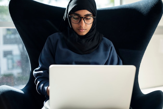 Ragazza islamica che si siede e che utilizza computer portatile