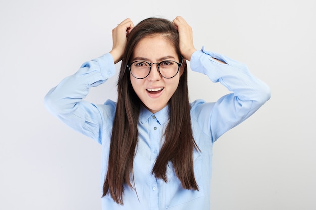 Ragazza kazaka con i vetri che tengono testa e grida isolati in studio bianco. Concetto di stress, nervoso, esaurimento