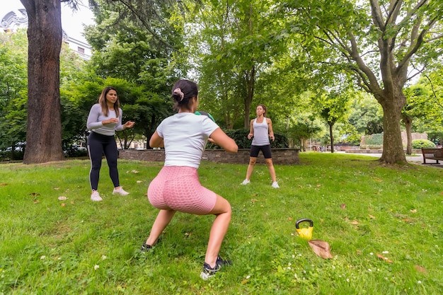Ragazza latina che fa esercizio e sport in un istruttore attento del parco verde nel gioco del passaggio della palla pesante