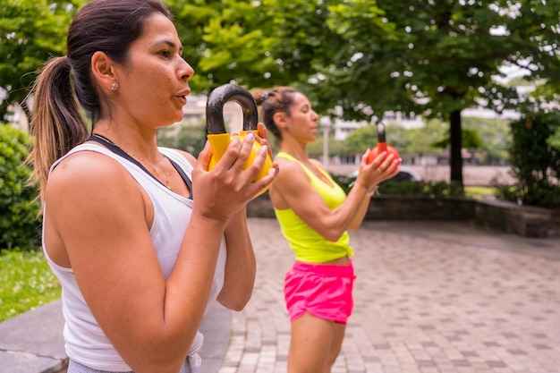 Ragazza latina che fa sport in un parco in città, stile di vita una vita sana, due ragazze che si esercitano con i pesi