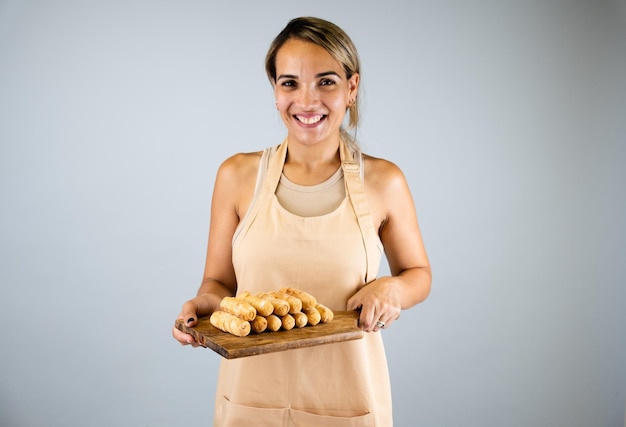 Ragazza latina che tiene una tavola di legno con tequenos appena cucinato cibo tipico venezuelano