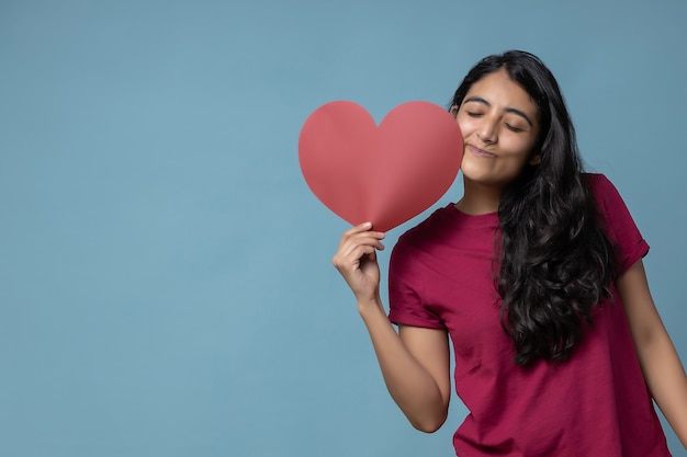 Ragazza latina messicana che tiene un San Valentino di carta a forma di cuore rosso