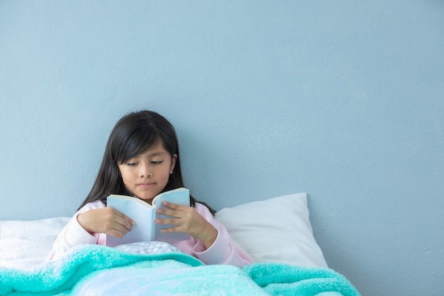 Ragazza latina sveglia a letto che legge un libro prima del sonno