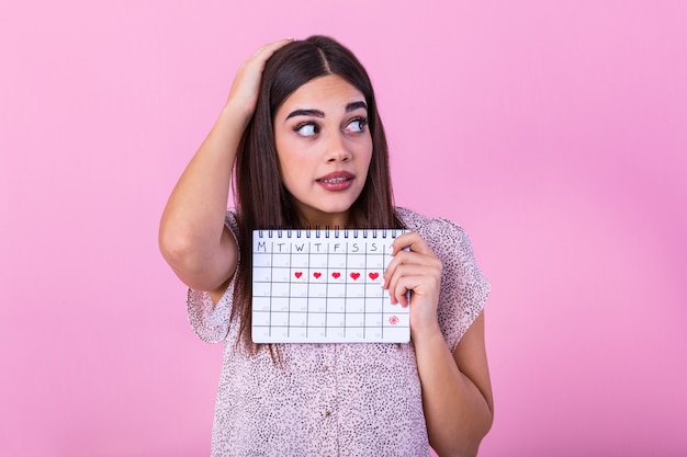 Ragazza magra imbarazzata che tiene calendario mestruale