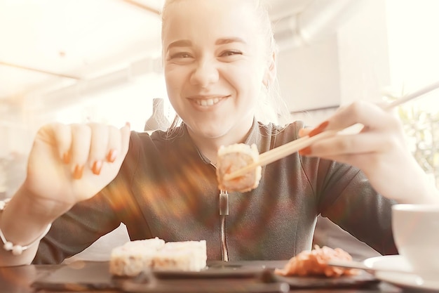 ragazza mangia sushi e panini in un ristorante / cucina orientale, cibo giapponese, giovane modella in un ristorante