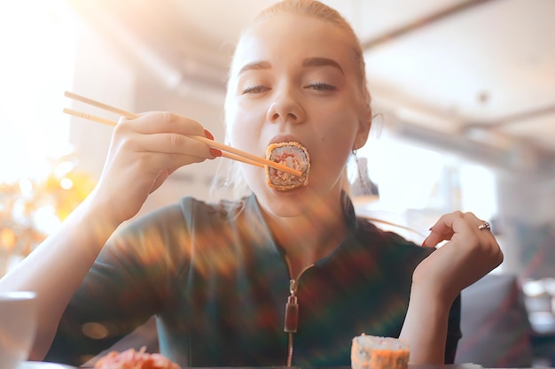ragazza mangia sushi e panini in un ristorante / cucina orientale, cibo giapponese, giovane modella in un ristorante