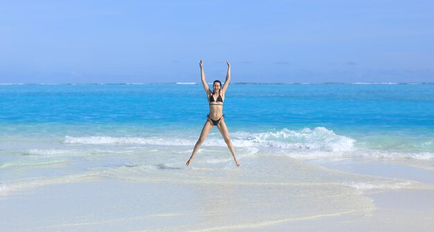 ragazza modello in un bikini nero sulla sabbia bianca in riva all'oceano